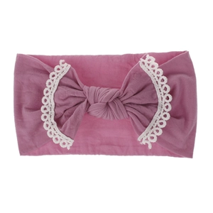 Detail of soft nylon baby headband featuring lace edges and dusty pink knotted bow
