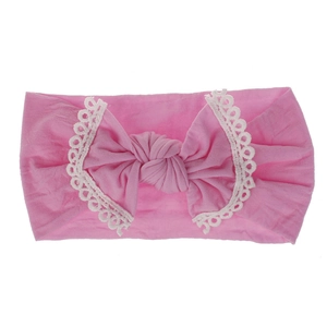 Detail view of pink soft nylon baby headband with lace-trimmed bow and knot.