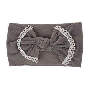 Close-up detail of a grey super soft nylon baby headband with a lace-trimmed bow