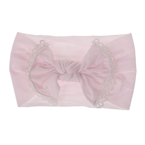 Detail view of a soft pink nylon baby headband featuring lace trim and a large bow design.