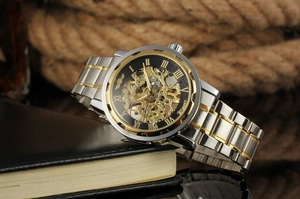 Détail de la montre squelette Winner avec chiffres romains dorés et bracelet en acier bicolore