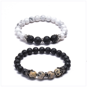 Detail of white turquoise and black lava stone bead bracelets with crown charms