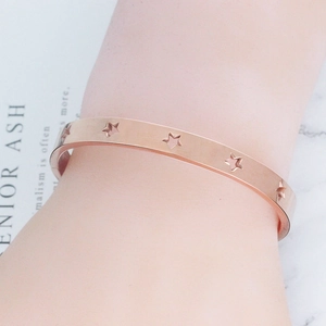 Close-up of rose gold stainless steel bangle featuring hollow star patterns on wrist