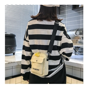 Canvas crossbody bag shown from a rear side angle on a model in a casual setting