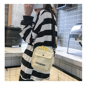 Close-up of cream canvas crossbody bag with yellow zipper and letter print