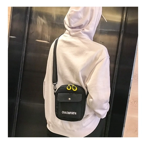 Detailed shot of black canvas crossbody bag with bright yellow double zippers and strap