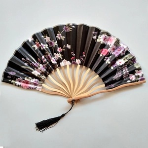 Japanese style folding fan with black silk surface, pink cherry blossoms, and black tassel