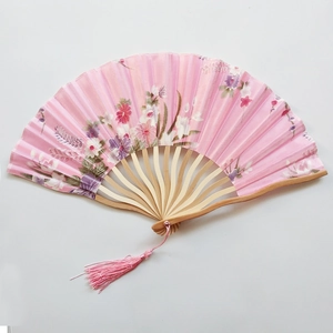 Detailed view of pink floral silk folding fan with bamboo ribs and matching tassel