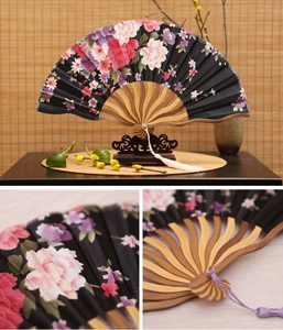 Close-up of Japanese style bamboo hand fan featuring floral patterns and silky tassels