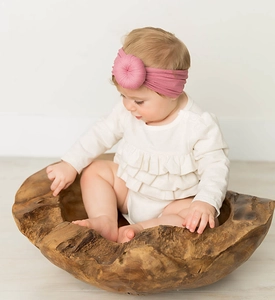 Dettaglio della fascia in nylon rosa con nodo a ciambella su un neonato in una ciotola