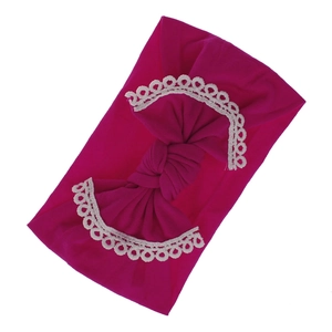 Macro view of soft fuchsia nylon baby headband featuring delicate white lace trim on bow