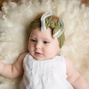 Detailed close-up of a baby girl wearing an olive green soft nylon headband with lace bow