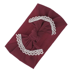 Detailed macro view of soft burgundy elastic headband with white lace bow decoration