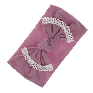 Detail of soft nylon baby headband with lace-edged bow in dusty pink color