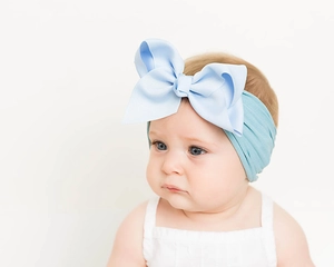 Nahaufnahme eines Babys mit einer großen hellblauen Schleife und weichem Nylon-Haarband