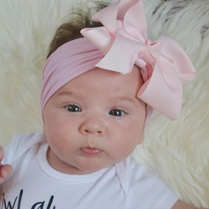 Detail eines rosa weichen Nylon-Babystirnbands mit großer Schleife auf einem Plüschteppich