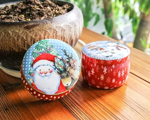 Detail of Christmas snowman and Santa Claus tin cans on a rustic wooden table surface