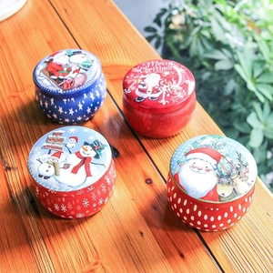 Set of round Christmas tin gift boxes with holiday illustrations on wooden table surface