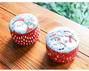 Macro detail of Christmas tin cans with Santa and Snowman prints on wooden surface
