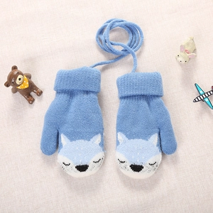 Close-up of blue knitted toddler mittens with fox pattern and neck string on soft fabric