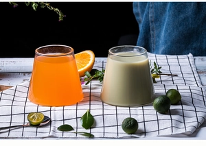 Detail view of Mount Fuji glass cups on checkered fabric with fresh citrus and juice