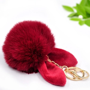 Close-up of fluffy red pompom keychain with soft rabbit ears and gold metal clasp
