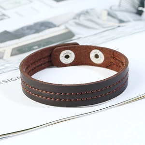 Brown leather bracelet with orange stitching and metal snap buttons on white background