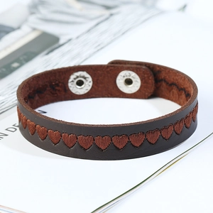 Brown leather bracelet with embroidered heart pattern and snap button closure
