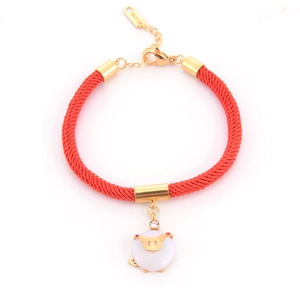 Detailed shot of red braided rope bracelet with gold pig charm and S-STEEL engraving
