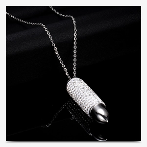 Detailed close-up of bullet pendant necklace with pavé-set crystals on black leather background