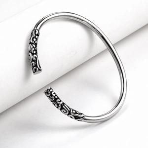 Detailed close-up of silver steel cuff with intricate engraved cloud pattern details