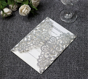 Close-up of laser-cut silver glitter invitation card featuring elegant hollow floral patterns