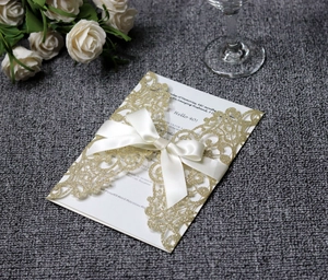 Detail of laser-cut gold glitter 40th birthday invitation with a white satin ribbon bow