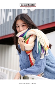 Detailed knit texture of colorful striped scarf with long fringe on blue sweater