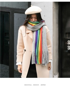 Detail of grey cashmere-like scarf with rainbow stripes and long tassels in winter scene