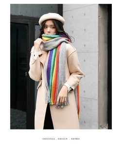 Detail of colorful rainbow striped scarf with fringe paired with a beige wool coat