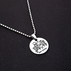 Detail of Best Teacher round pendant with ball chain on dark textured background