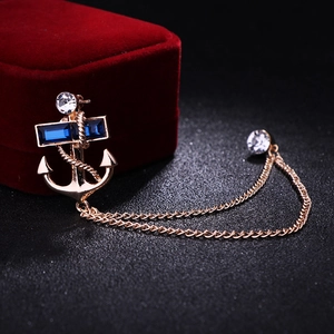 Detail of anchor brooch with blue crystals and gold tassels on black texture background