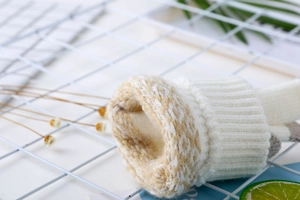 Gants en tricot blanc avec revers en peluche à motifs beiges et texture douce en gros plan