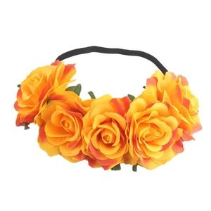 Close-up of orange-yellow faux roses and green leaves on an elastic bohemian headband