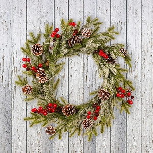 Frosted Christmas wreath with pine cones and red berries on a vintage wooden background