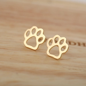Minimalist gold-plated hollow paw print stud earrings on a natural wood surface