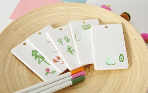 DIY hand-painted white ABS plastic card sleeves displayed on a wooden tray with color pencils