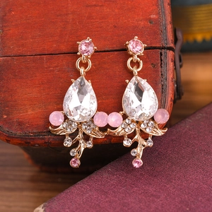 Close-up of vintage gold drop earrings with pink crystals on a mahogany jewelry box