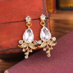 Close-up of vintage bridal earrings with teardrop crystals and gold leaf-shaped details