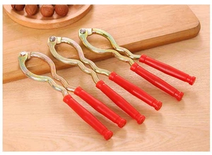 Close-up of red handle nutcrackers on a wooden table with a bowl of walnuts