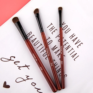 Detailed view of three professional pony hair eyeshadow brushes with red wood handles