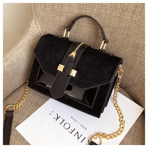 Detail of black leopard texture handbag with golden chain strap on a textured seat