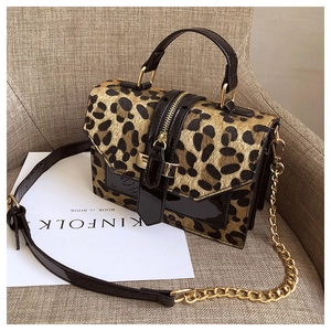 Detail of leopard print crossbody bag with gold hardware and chain strap on a seat