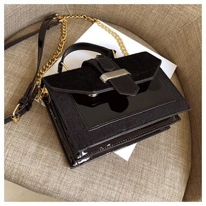 Detail of black glossy patent and matte leather stitching bag with gold chain